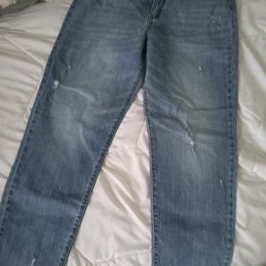 Distressed denim jeans. Light blue denim. Loose fit, greying at bottom.